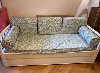 Sofá-cama de madera con cojines estampados