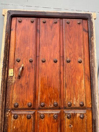 Puerta principal de madera antigua con herrajes