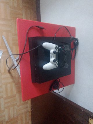 PlayStation 4 (PS4) con 2 mandos y una mesa