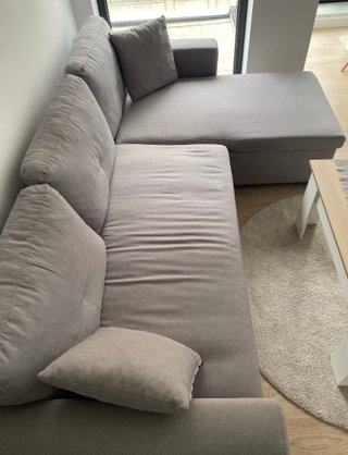 Sofá cama de tres plazas con chaise longue gris.