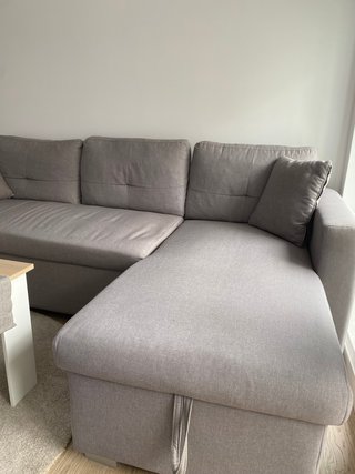 Sofá cama de tres plazas con chaise longue gris.