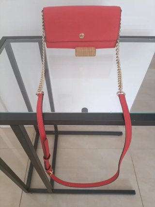 Bolso de mano de color coral con cadena dorada.