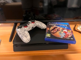 PS4 Slim con mando personalizado y juegos.