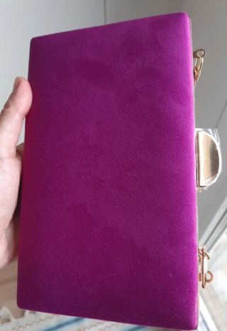 Bolso de mano fucsia con cadena dorada.
