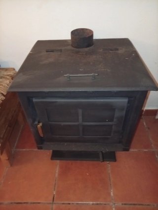 Estufa de leña con horno y dos tramos de tubo.