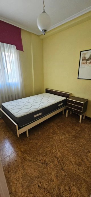 Dormitorio individual con cama y mesita