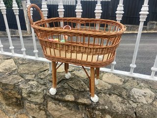 Cuna de mimbre para muñecas con ruedas