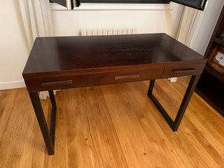 Escritorio de madera marrón con patas de hierro.