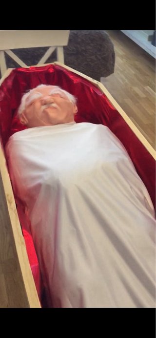 Ataúd con figura  anciana en silla