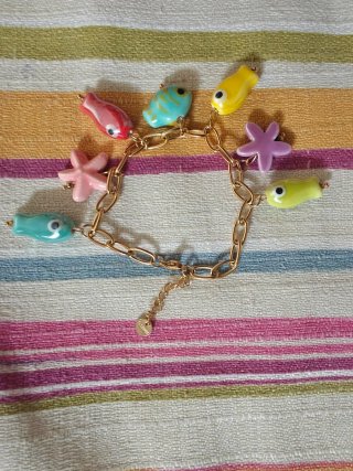 Pulsera dorada con dijes de peces y estrellas