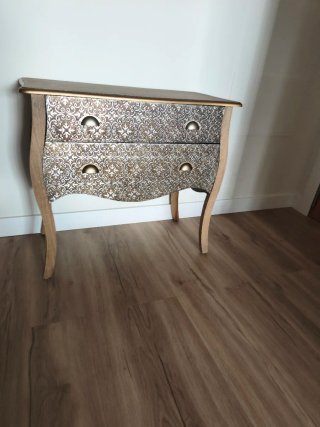 Cómoda vintage con detalles decorativos en metal.