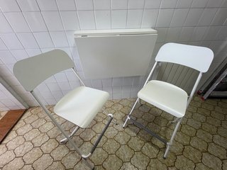 Mesa plegable y 2 sillas blancas.