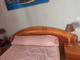 Dormitorio de madera con cabecero y mesitas