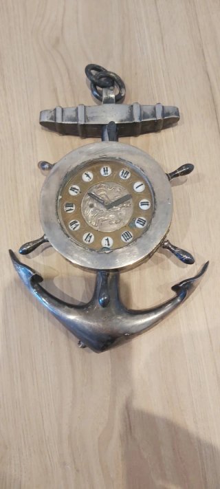 Ancla decorativa plateada con detalle reloj.