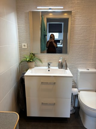 Mueble de baño blanco con espejo y grifo