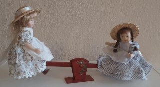 Coppia di bambole in porcellana con altalena