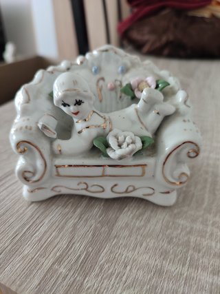 Figura porcelana decorativa de una niña en el sofá