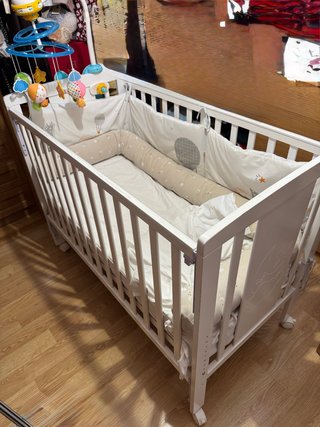 Cuna blanca con protector y móvil