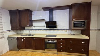 Cocina completa de madera y encimera de piedra.